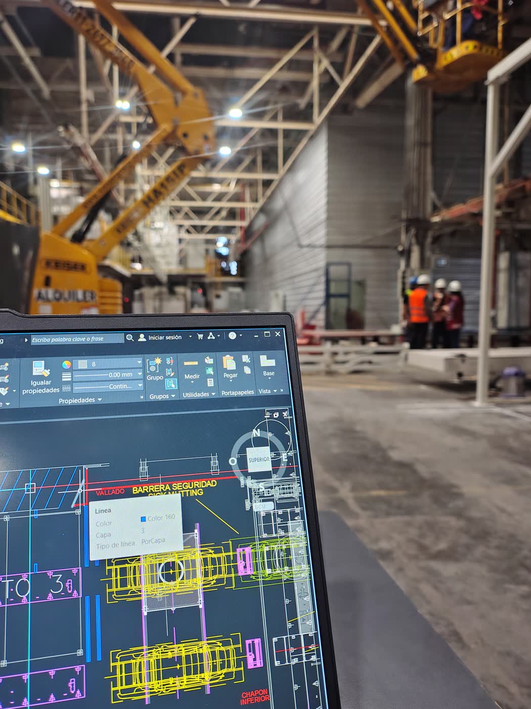Plano CAD en pantalla superpuesto a estructura real en obra durante verificación técnica