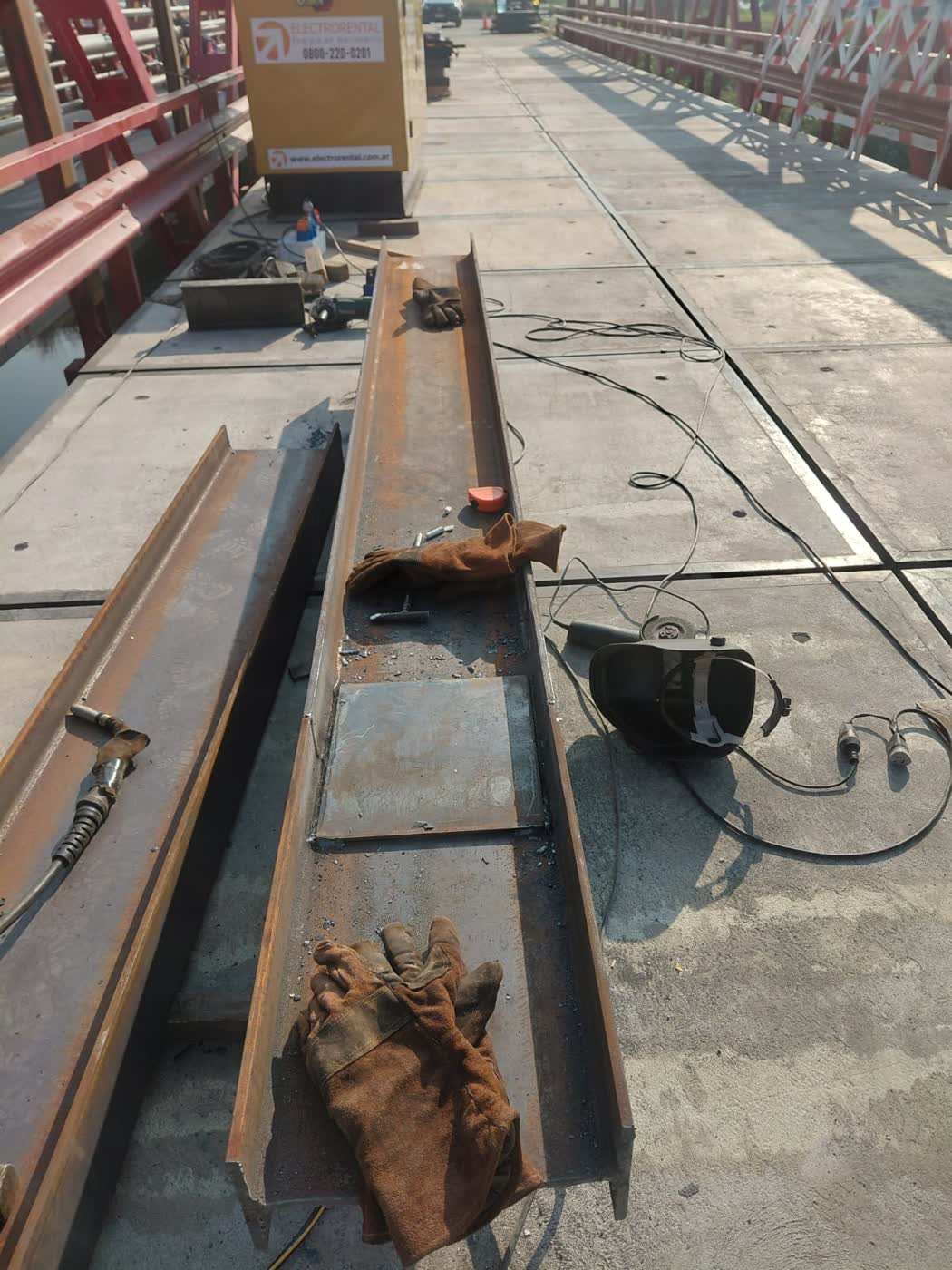 Operarios trabajando sobre estructura de puente metálico a la vera de un río