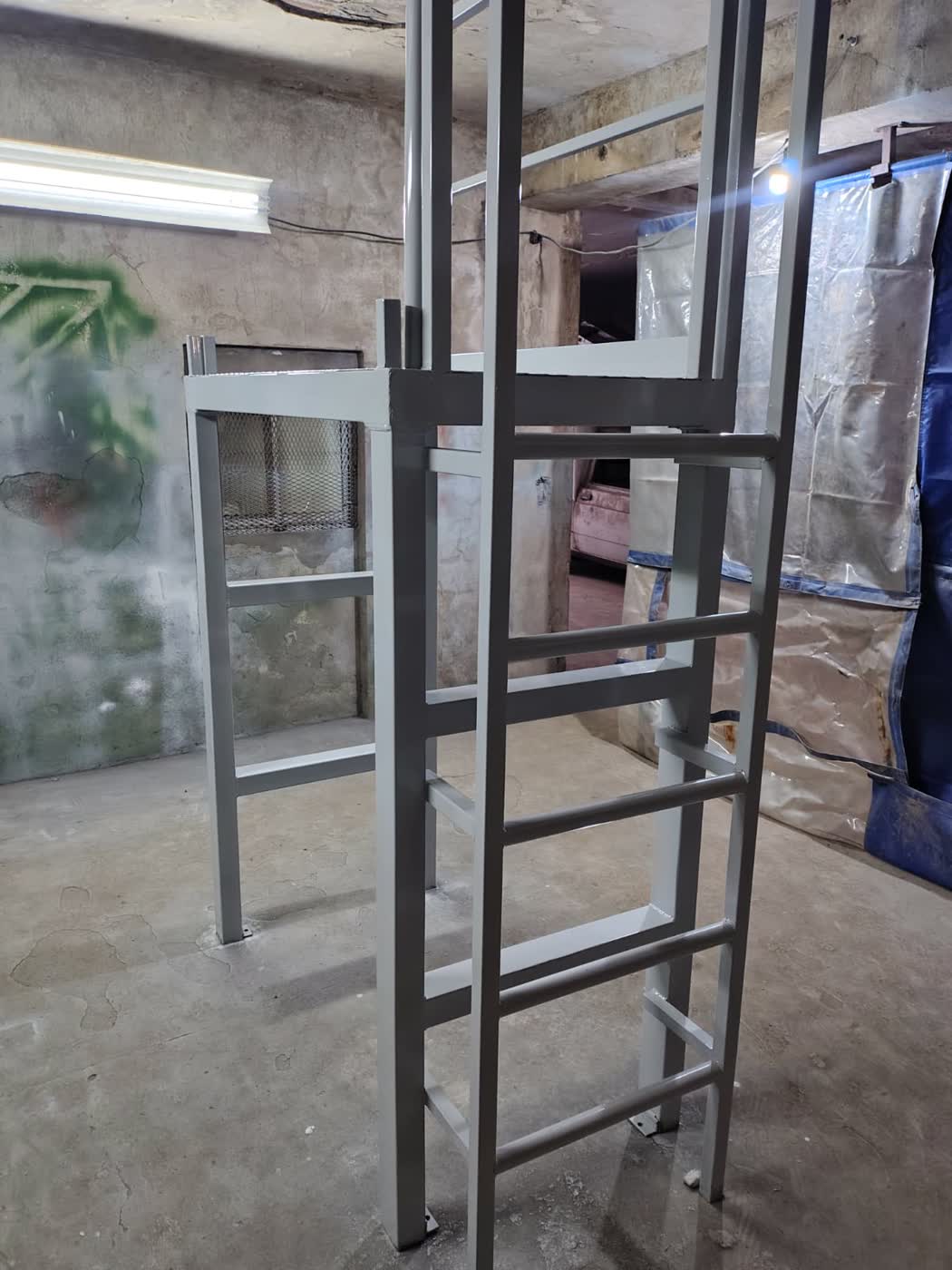 Plataforma metálica de acceso con escalera pintada de gris para máquina industrial