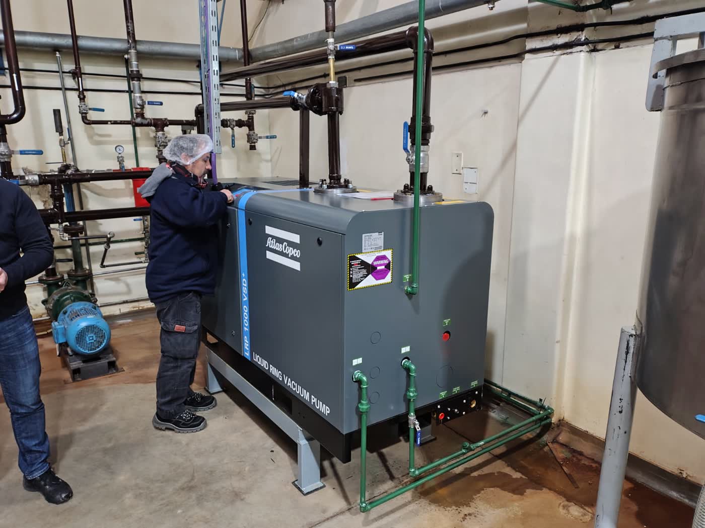 Técnico ajustando bomba de vacío industrial en sala de máquinas